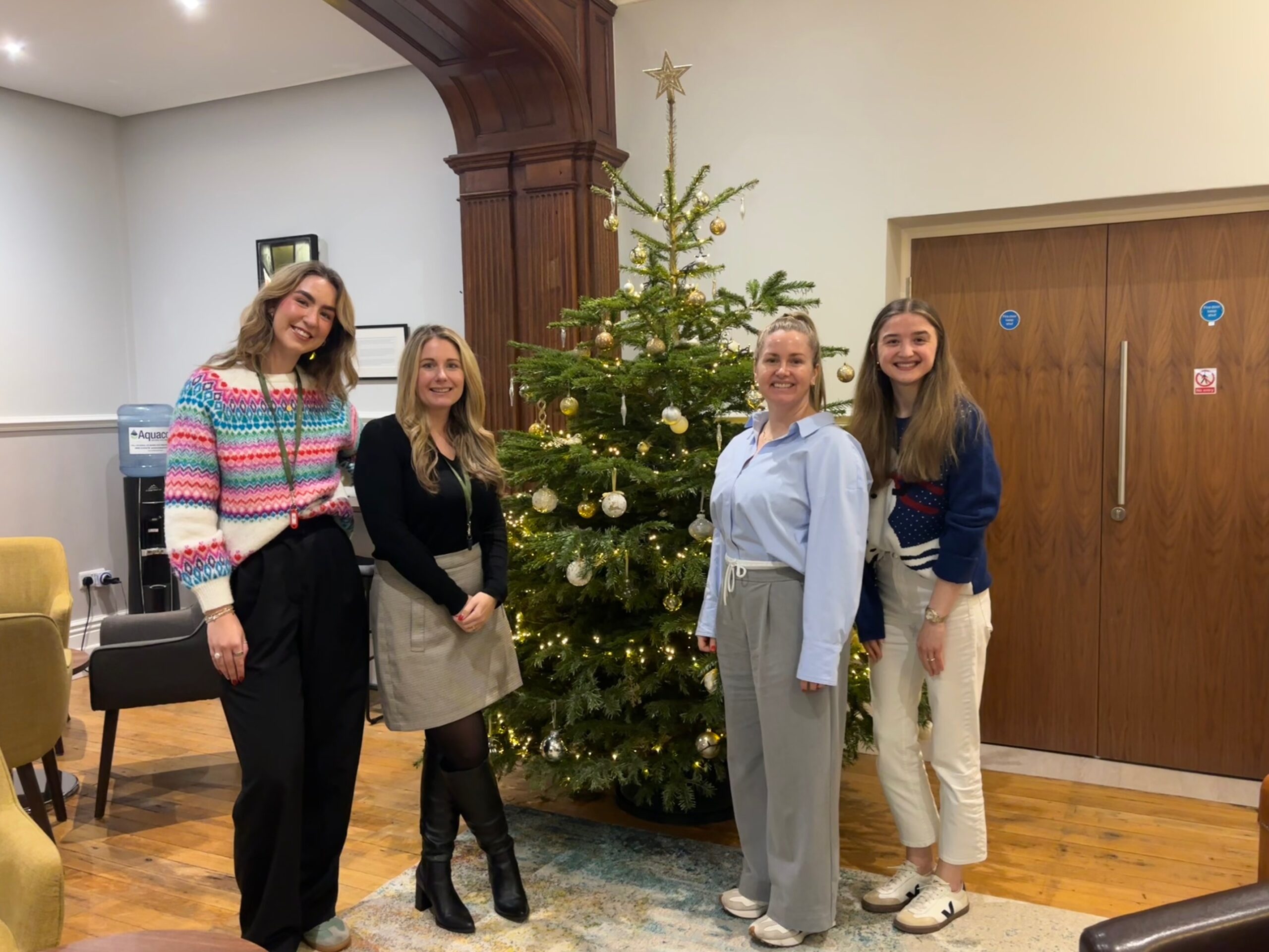 The MacMartin Team posing in front of a Christmas Tree